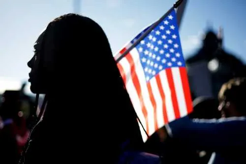 Silhouette of a young Black woman beside the American flag
