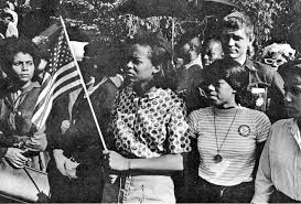 Black women marching with American flag during civil rights era